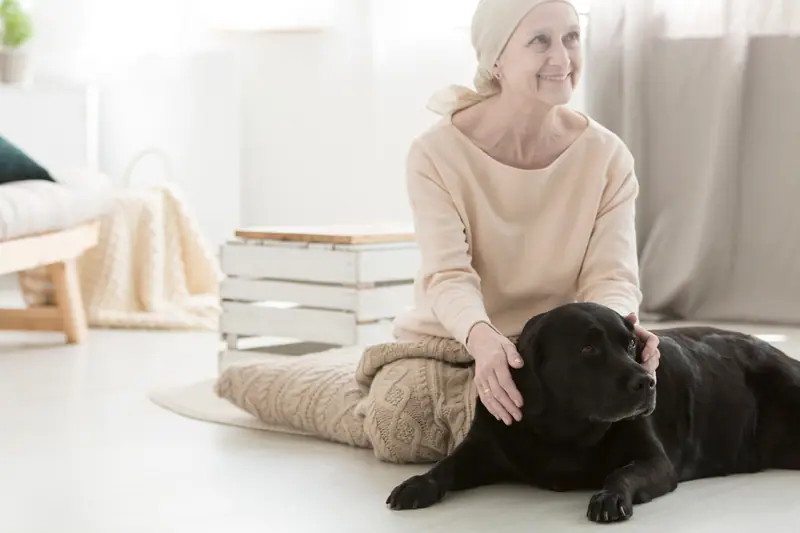 Woman in headscarf petting a black Labrador at home